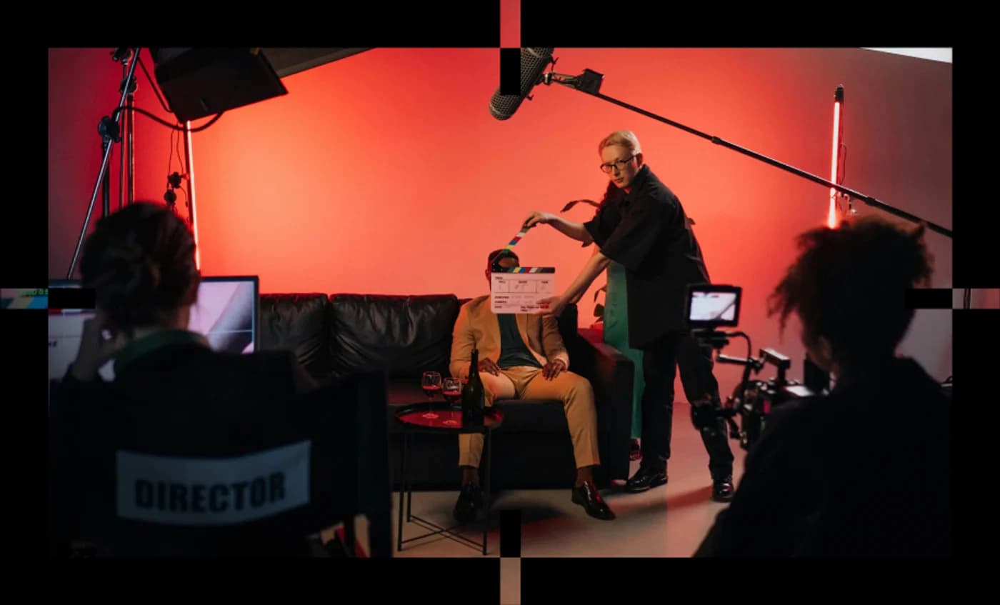 Red-lit film set with crew and a boom mic, framed with registration marks