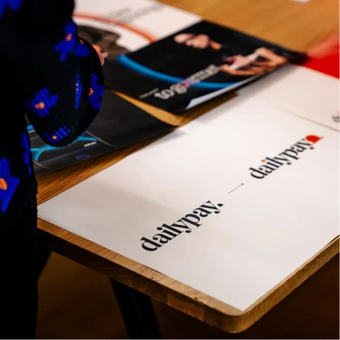 Two designers leaning over printed layouts spread across a studio table